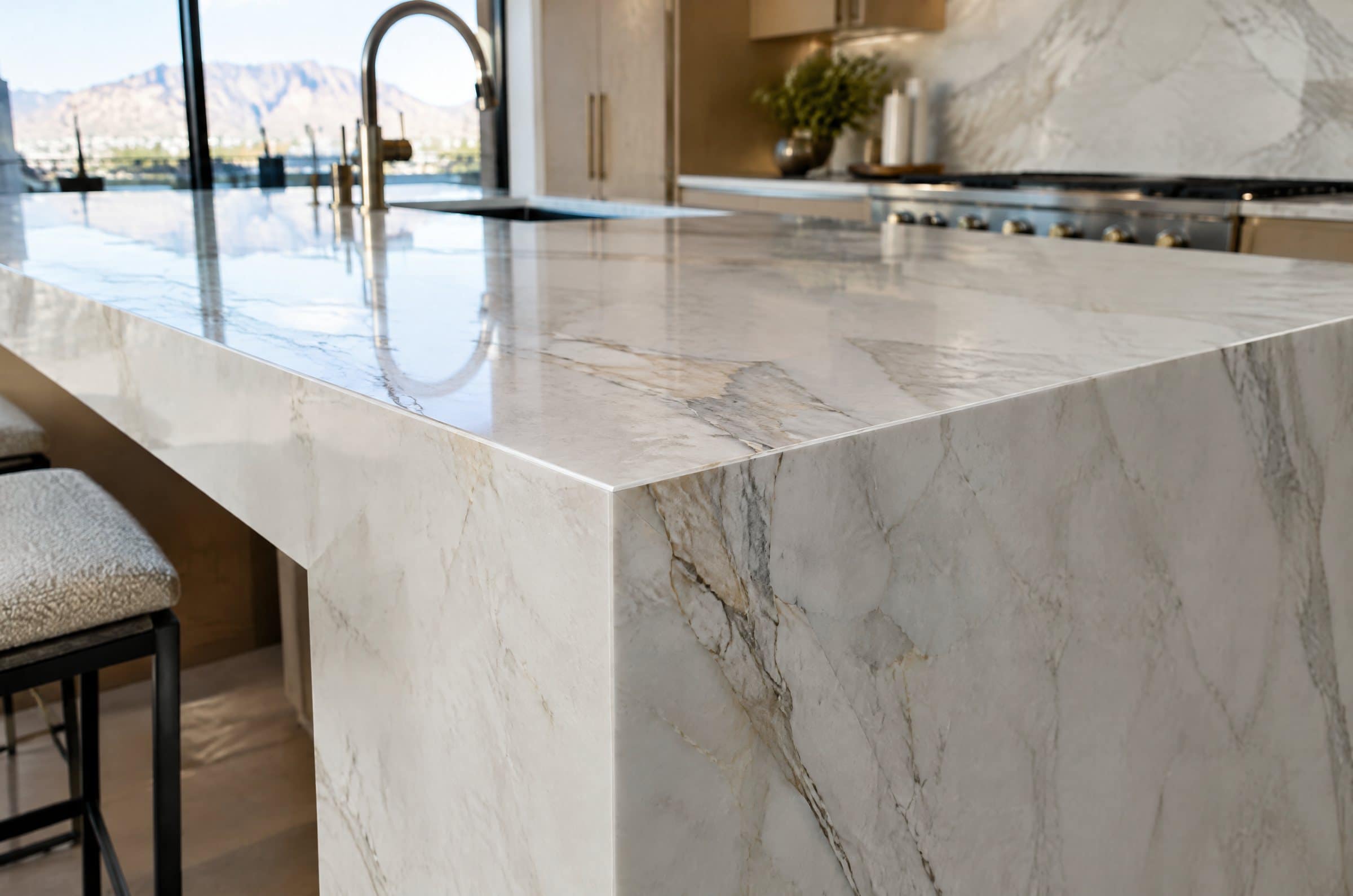 Close-up of a mitered waterfall corner on a white quartzite island, veining wrapping the edge